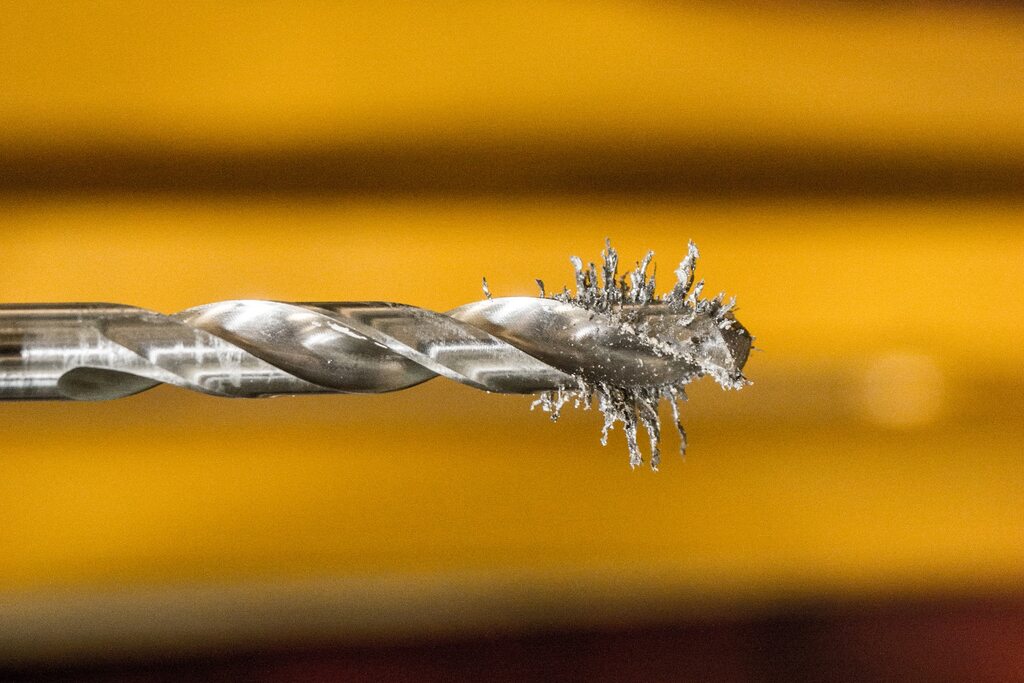 Amolador de brocas, detalhe de broca com lascas de metal simbolizando desgaste