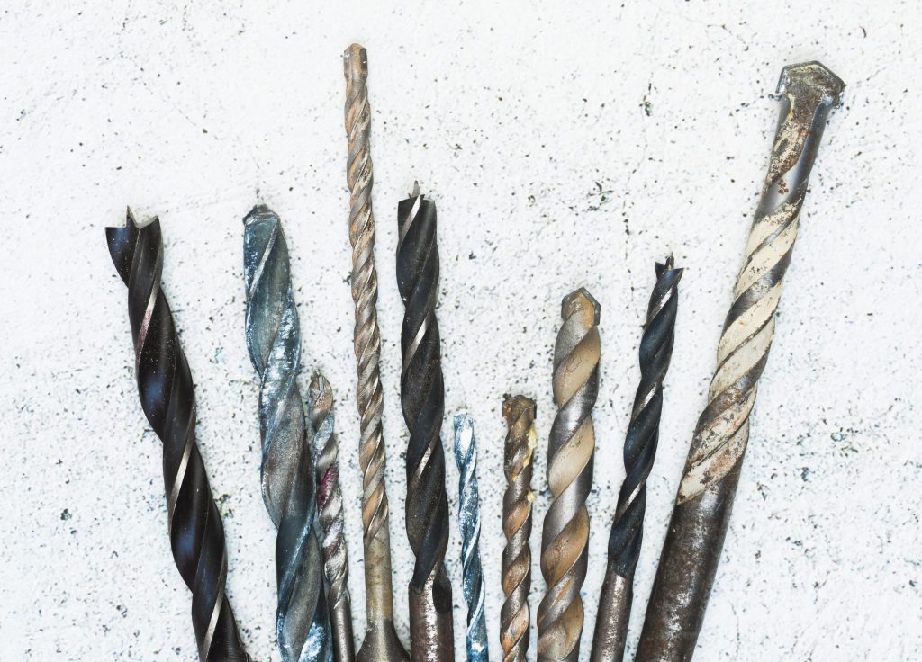 Brocas desgastadas de diferentes tamanhos vistas de cima, utilizadas em perfuração industrial